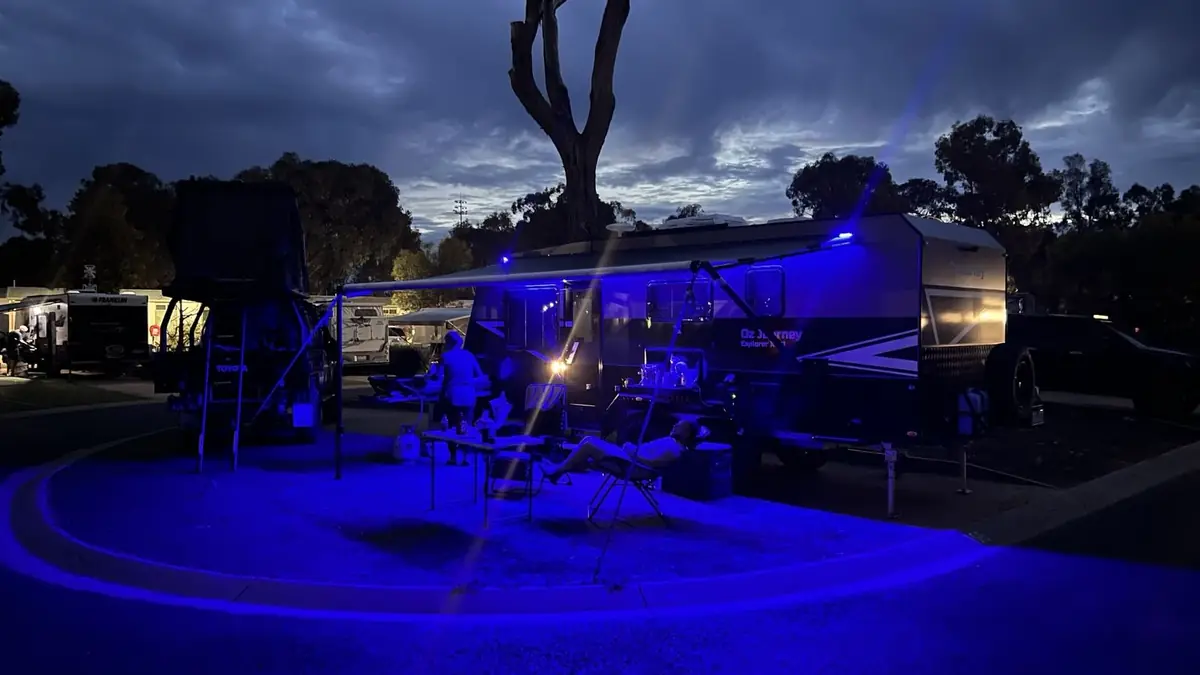 Explorer X621 at night with blue LED awning lights glowing across the campsite